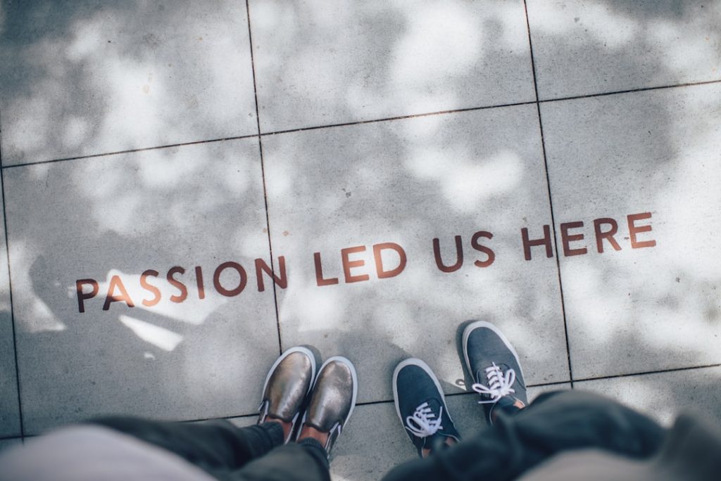 Zwei Personen von Promobildertexte stehen auf einem Bodenschriftzug "Passion led us here"